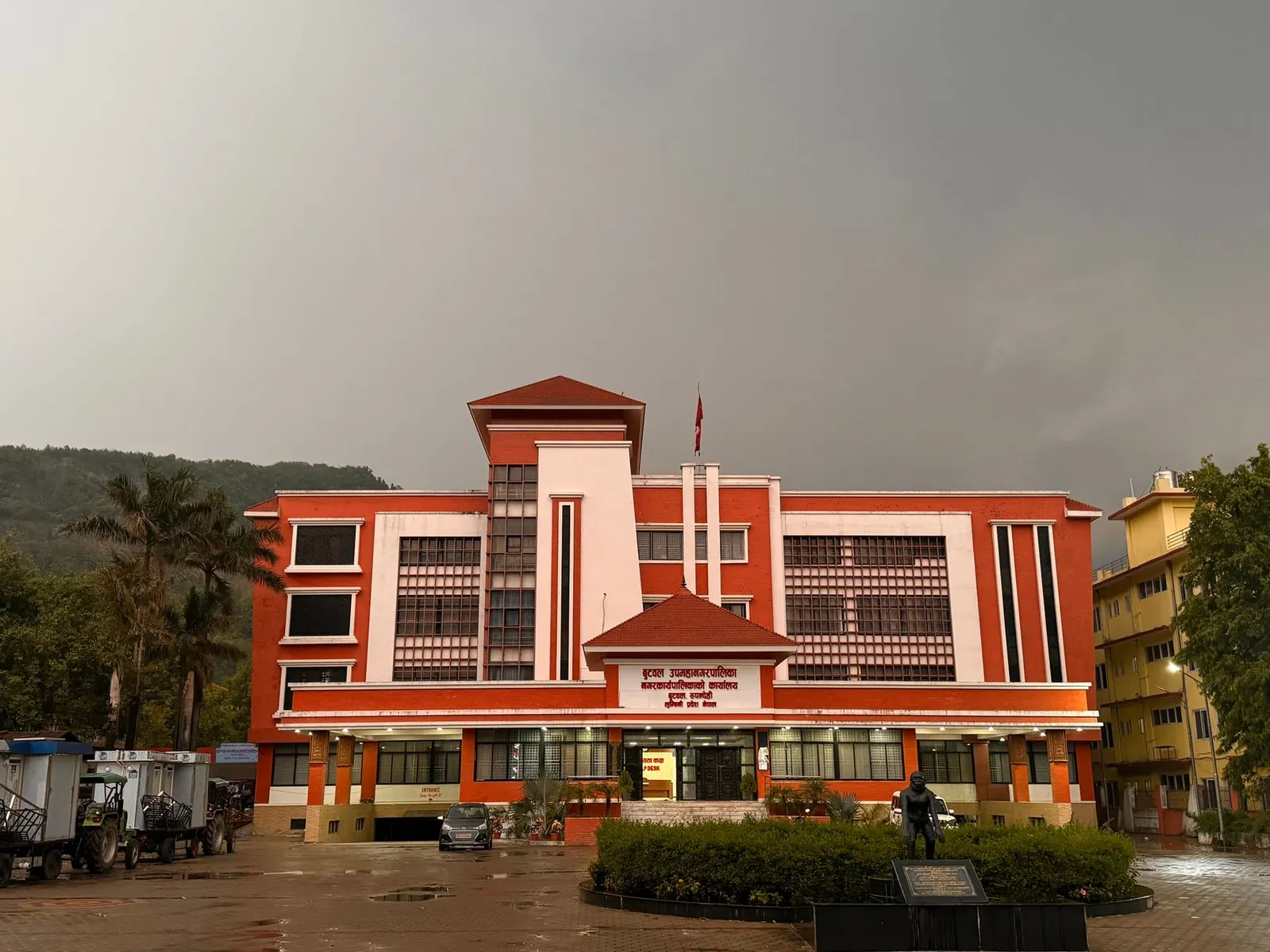 A striking red government building stands under an overcast sky, featuring modern architecture. Stock photo illustrating Utkarsh Small Finance Bank's fund raise story.
