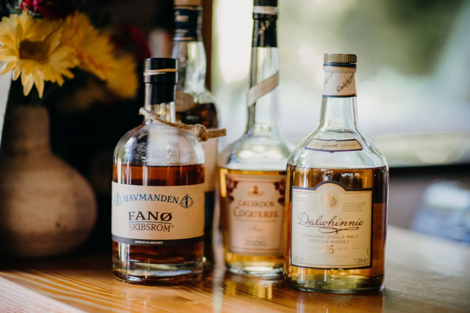 Close-up of premium whiskey and rum bottles displayed on a wooden surface. Stock photo illustrating Allied Blenders and Distillers' product launched story.