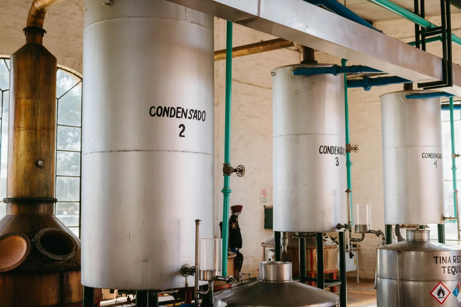 Interior view of industrial tequila distillery with metal tanks and pipes. Stock photo illustrating Tatva Chintan Pharma Chem's expansion story.