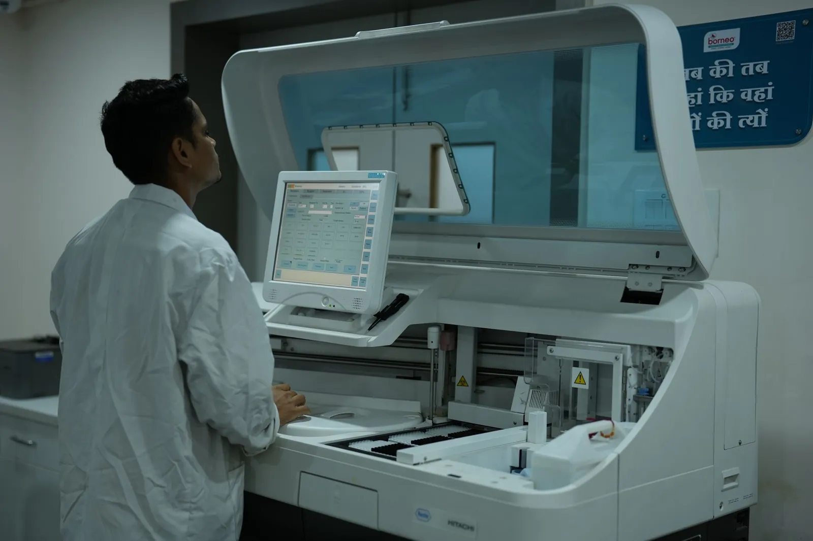 A lab technician operates a clinical analyzer in a modern laboratory setting. Stock photo illustrating Metropolis Healthcare's earning call story.
