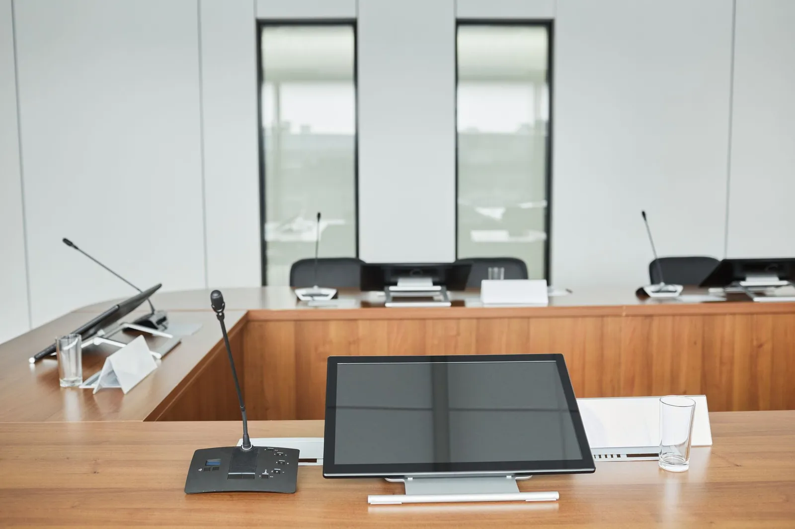 Empty conference room setup with microphones, monitors, and sleek wooden tables ready for meetings. Stock photo illustrating Purple Finance's fund raise story.