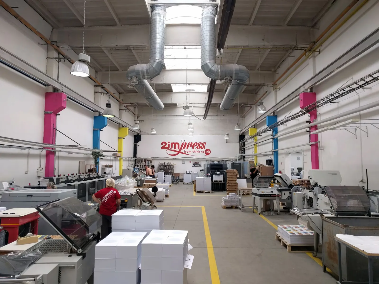 Spacious printing facility with modern machinery and workers engaging in tasks. Stock photo illustrating True Colors' product launched story.