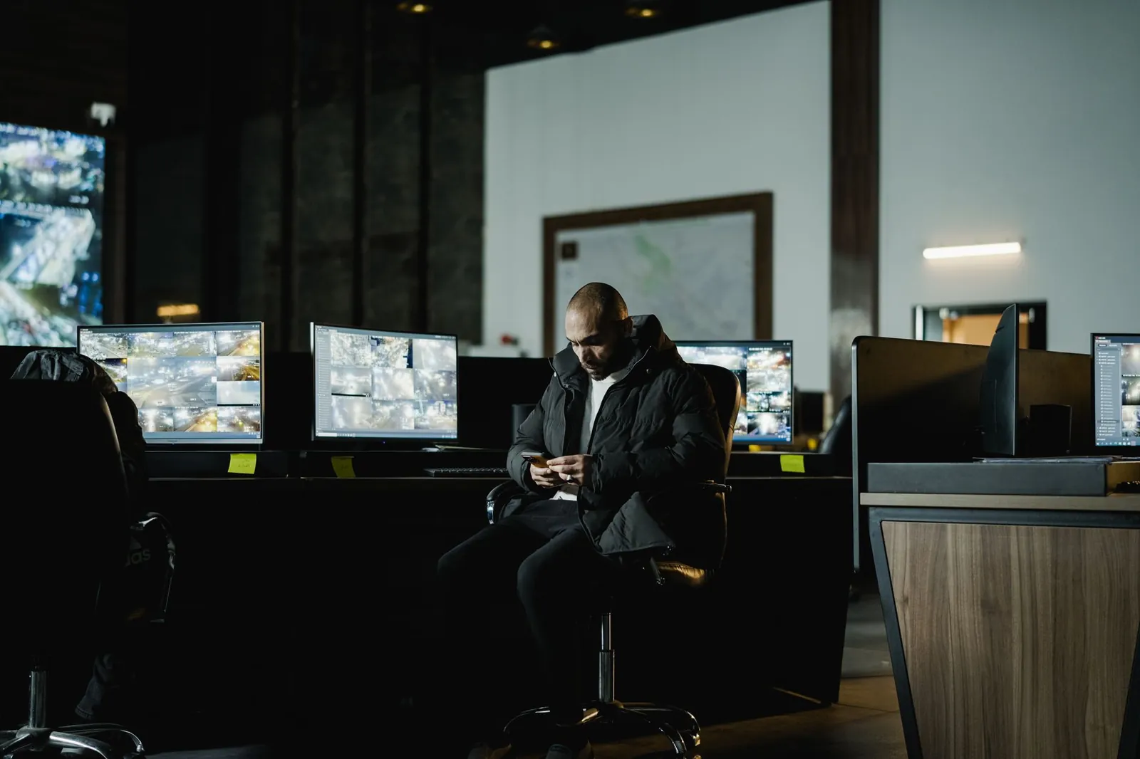 Security officer seated in a dimly lit control room, analyzing multiple surveillance screens. Stock photo illustrating Redington's earning call story.
