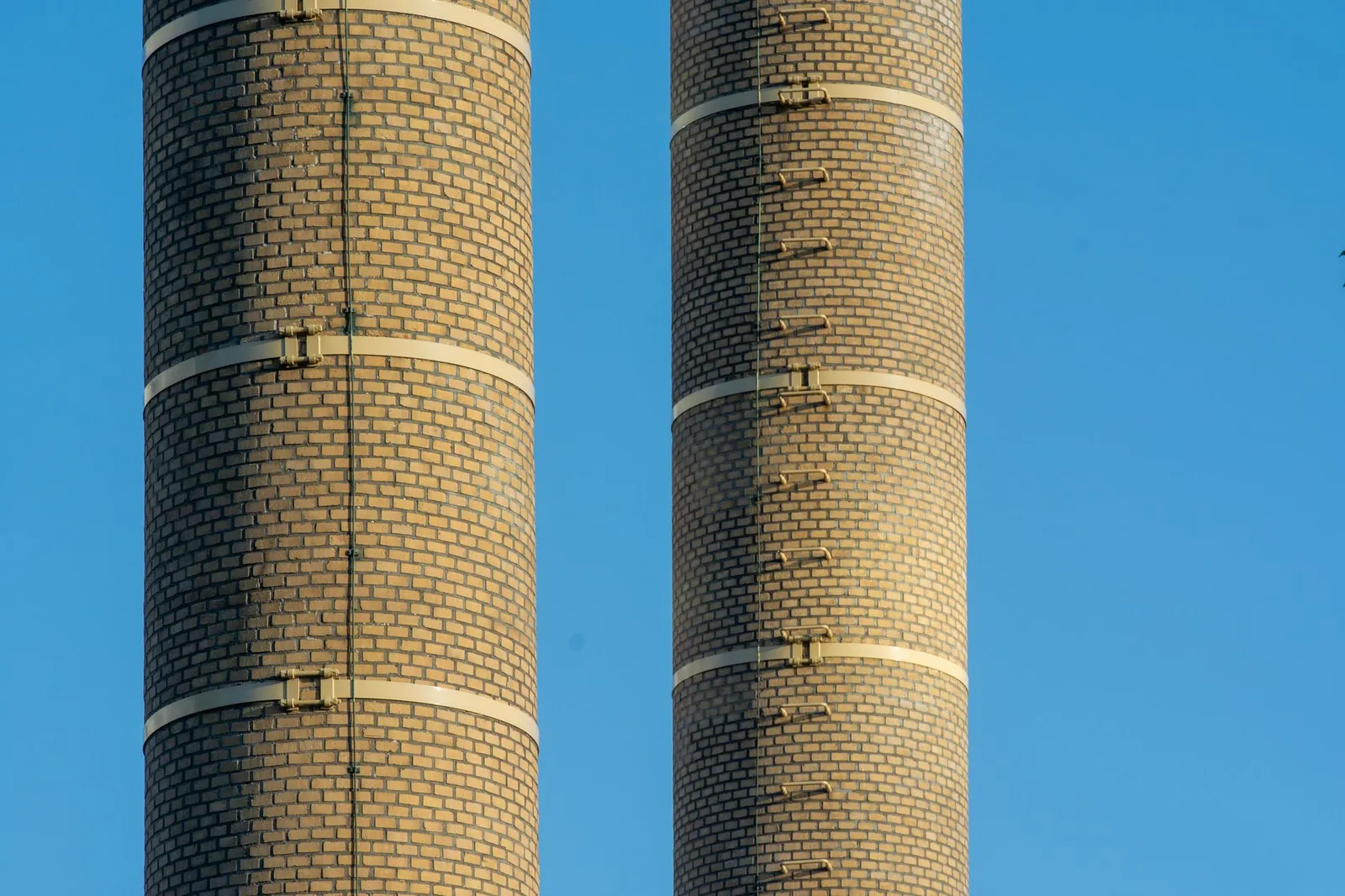 Close-up of two brick chimneys in an industrial setting under a clear blue sky. Stock photo illustrating Monolithisch India's earning call story.