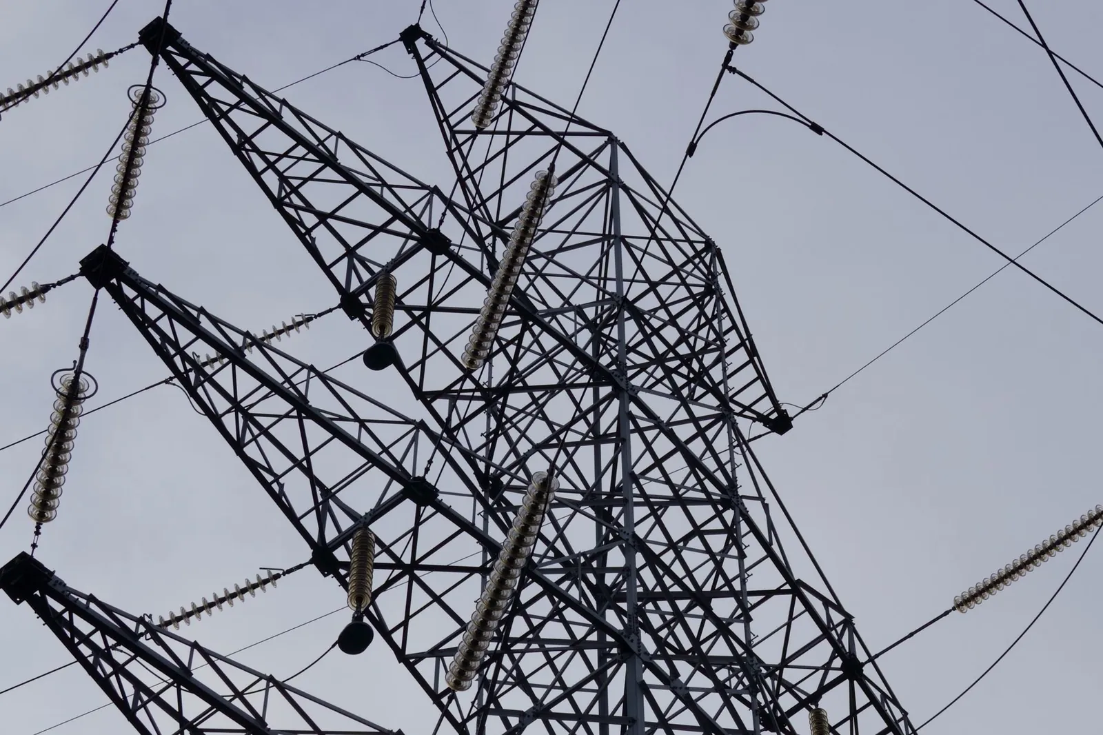 Low angle shot of a metal power transmission tower with cables against a clear sky. Stock photo illustrating Kalpataru Projects International's new order story.
