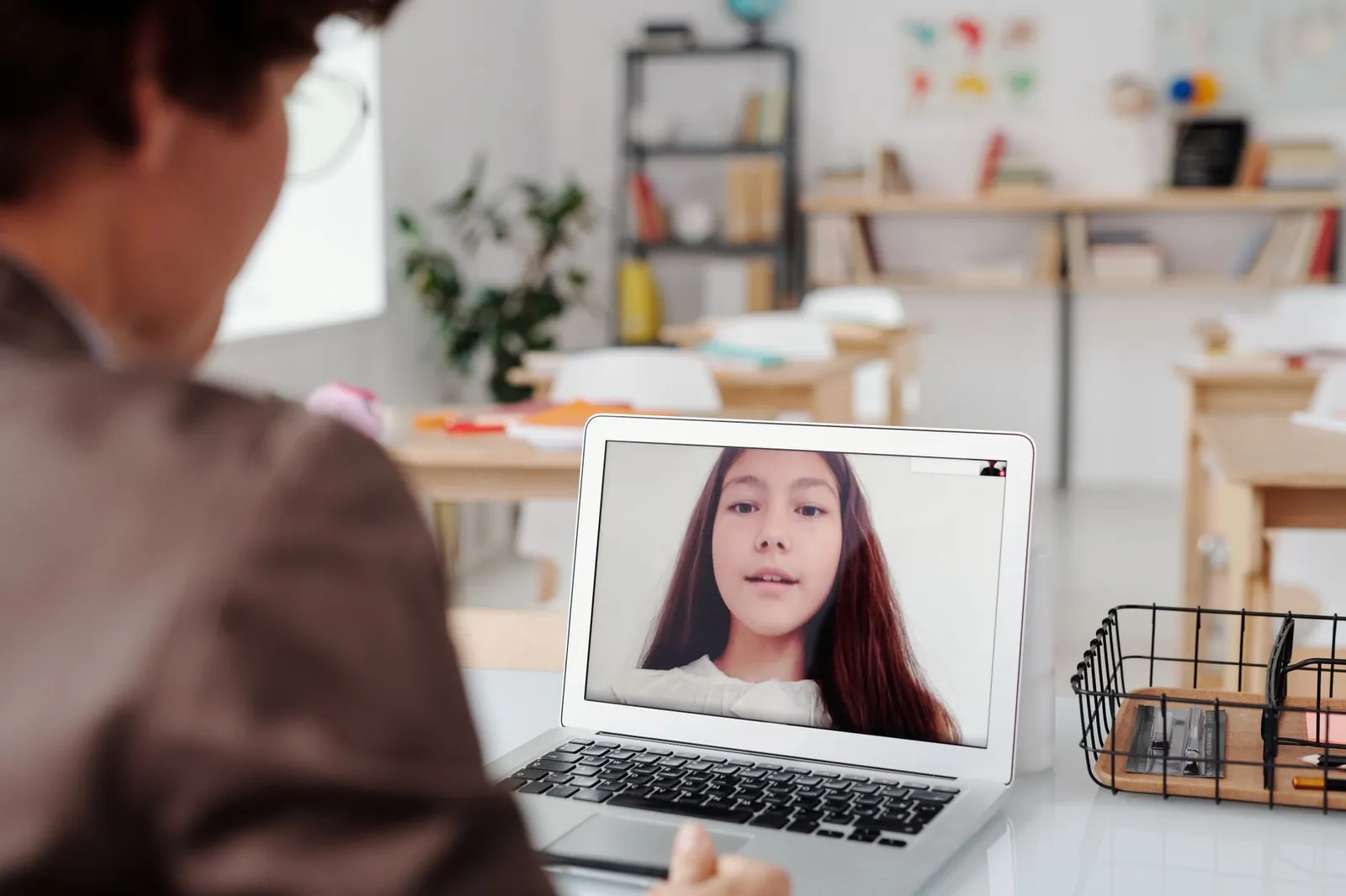 Teacher using laptop for virtual lesson with female student on screen in classroom setting. Stock photo illustrating Career Point Edutech's new order story.