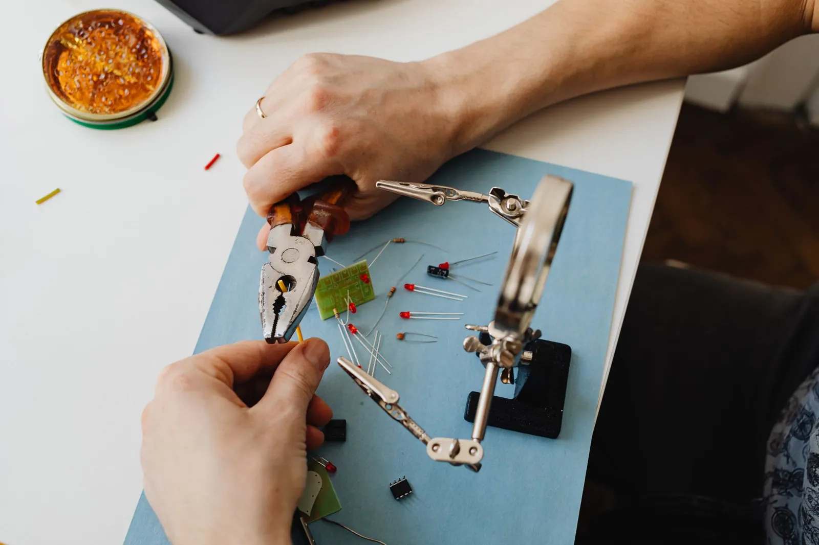 Close-up view of hands using tools to assemble electronic components with precision on a desk. Stock photo illustrating Greaves Cotton's fund raise story.