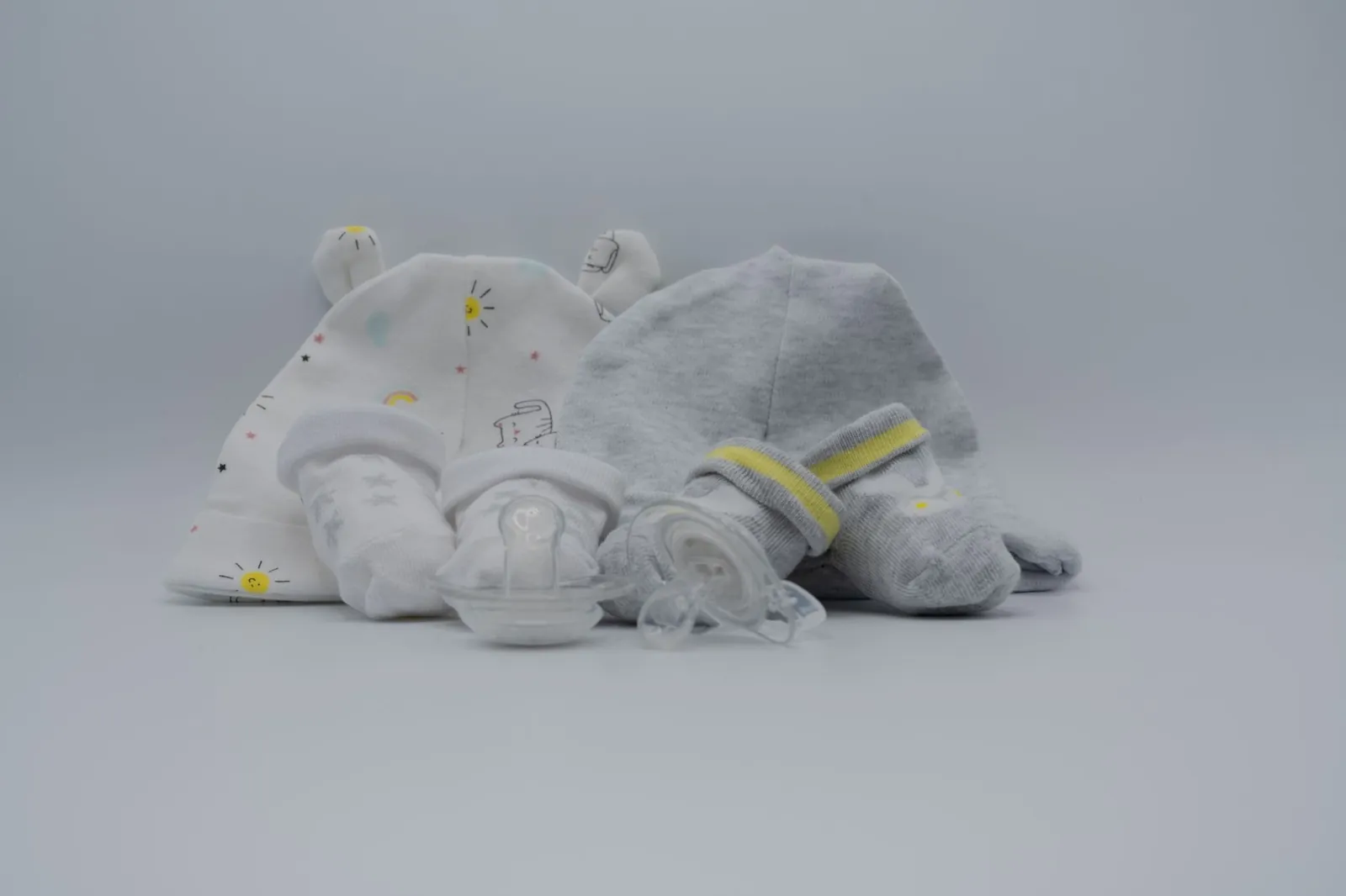 Cozy baby hats, socks, and pacifier in soft pastel colors. Perfect for newborns. Stock photo illustrating Iris Clothings' product launched story.