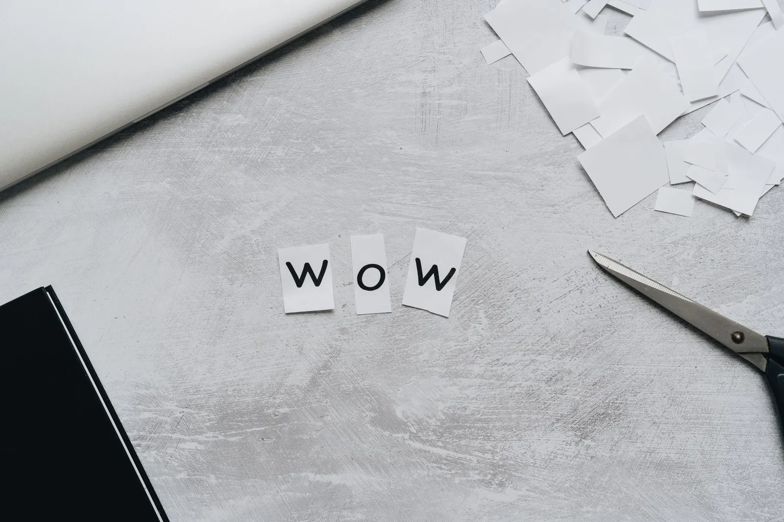 Crafted 'Wow' word with cutout letters, scissors, and paper for artistic projects. Stock photo for the ALFA News guide: Letter of Intent vs Work Order: A Guide for Indian Stock Investors.
