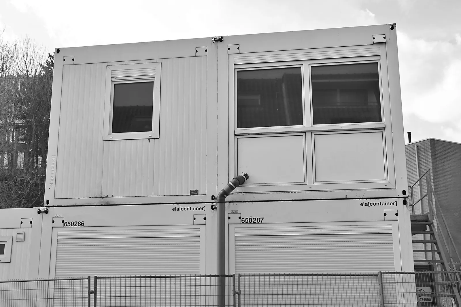Monochrome image of a stacked container building at a construction site. Stock photo illustrating Modulex Construction Technologies' new order story.