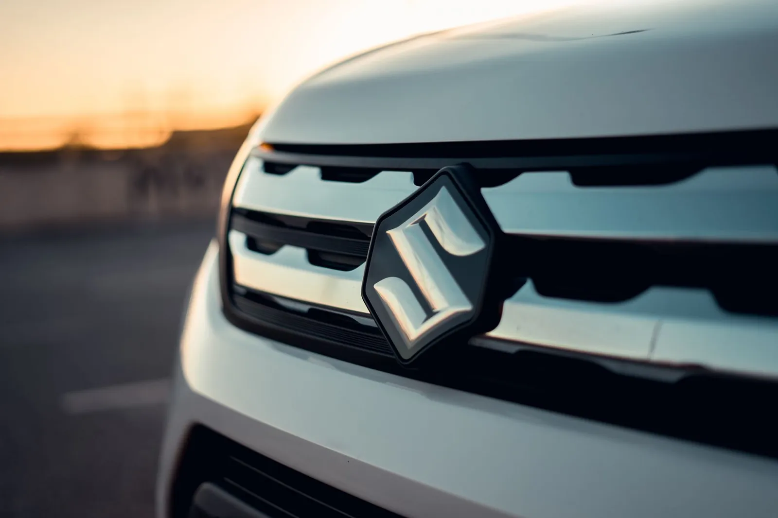 Detailed view of Suzuki car grille and logo captured at sunset, showcasing modern automotive design. Stock photo illustrating Maruti Suzuki India's product launched story.