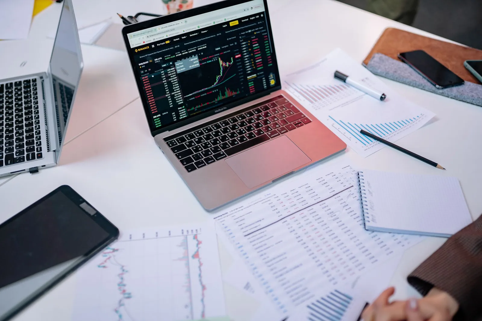 Laptops on a desk displaying stock market charts and financial documents. Stock photo illustrating Tata Consultancy Services' partnership story.