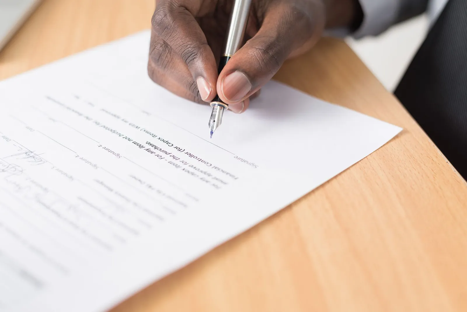 A hand holding a pen signing a document close-up on a desk, symbolizing agreement or contract finalization. Stock photo illustrating Krystal Integrated Services' new order story.