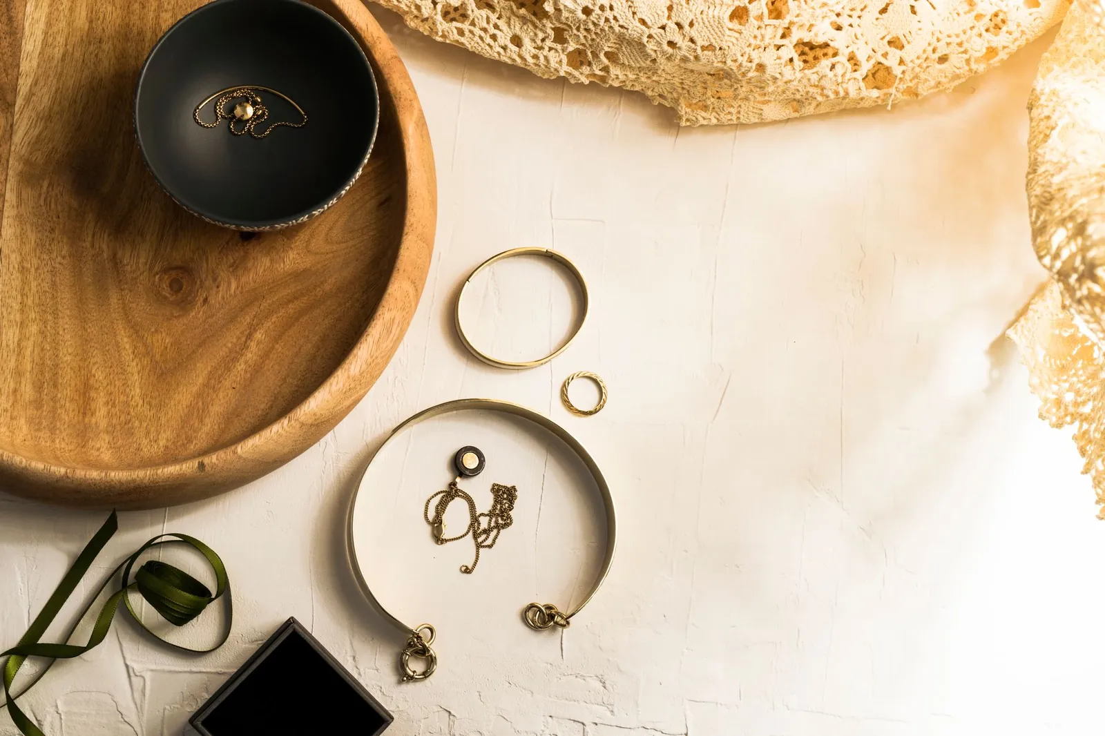 Elegant display of gold jewelry on a wooden tray with top view on a white surface. Stock photo illustrating Grover Jewells' fund raise story.