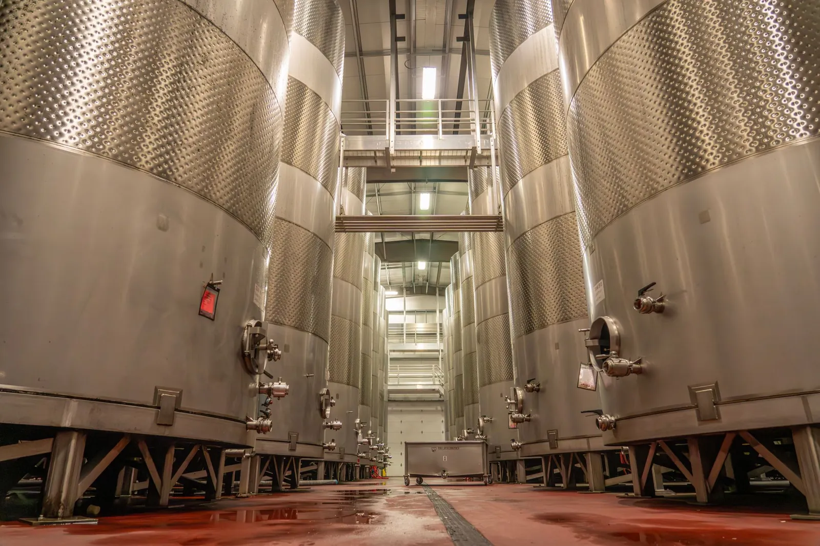 Interior of an industrial brewery with large, stainless steel fermentation tanks. Stock photo illustrating TANFAC Industries' fund raise story.