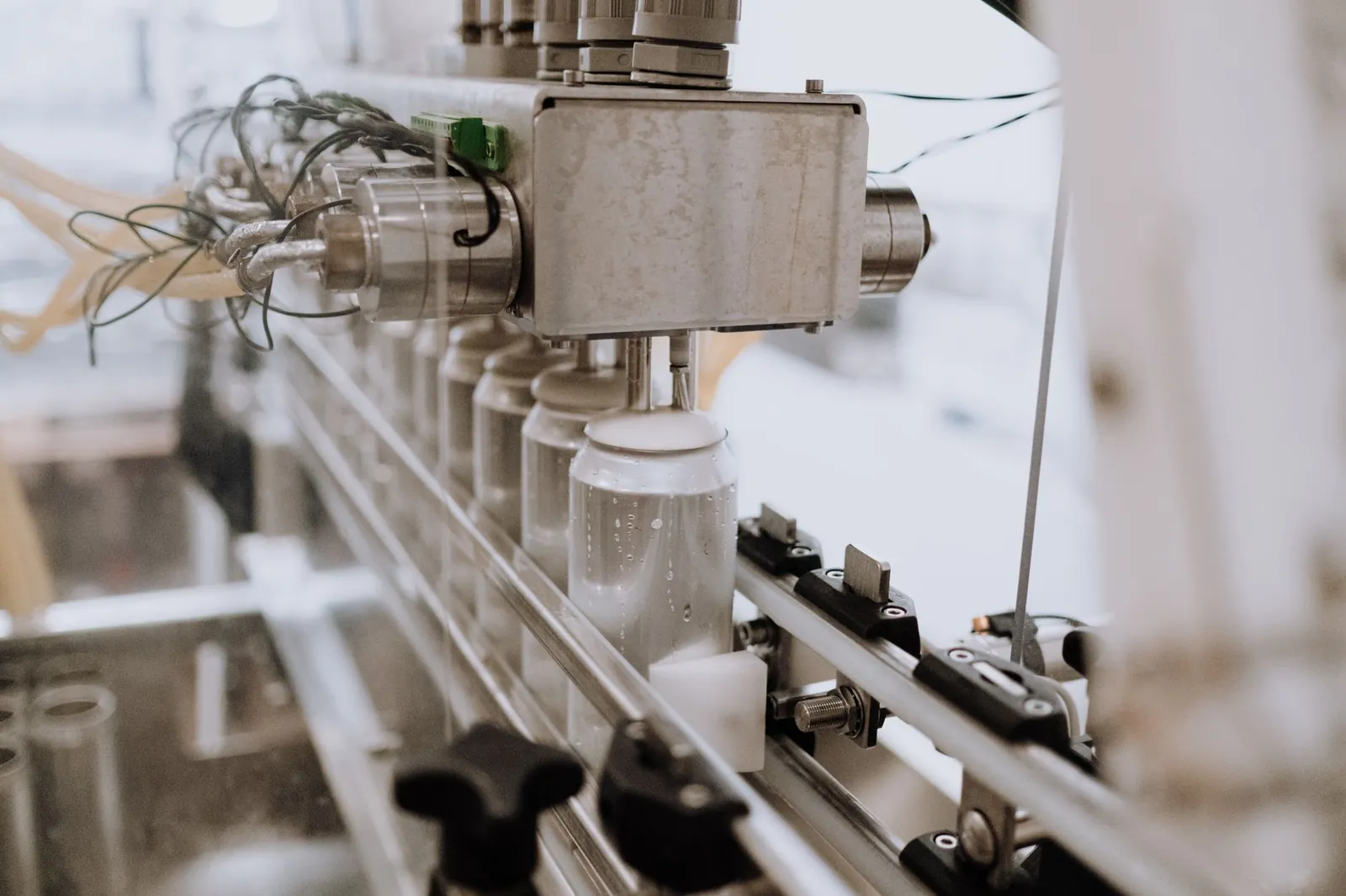 Close-up of an automated can filling machine in a beverage production line. Stock photo illustrating Neueon Corporation's fund raise story.