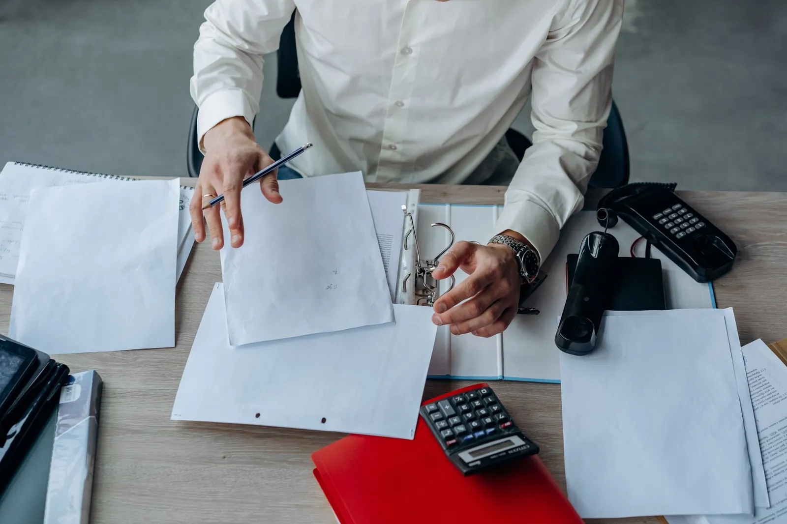 A business professional organizing documents at a busy office desk, emphasizing productivity. Stock photo for the ALFA News guide: XBRL Filings in India: A Guide for Investors.