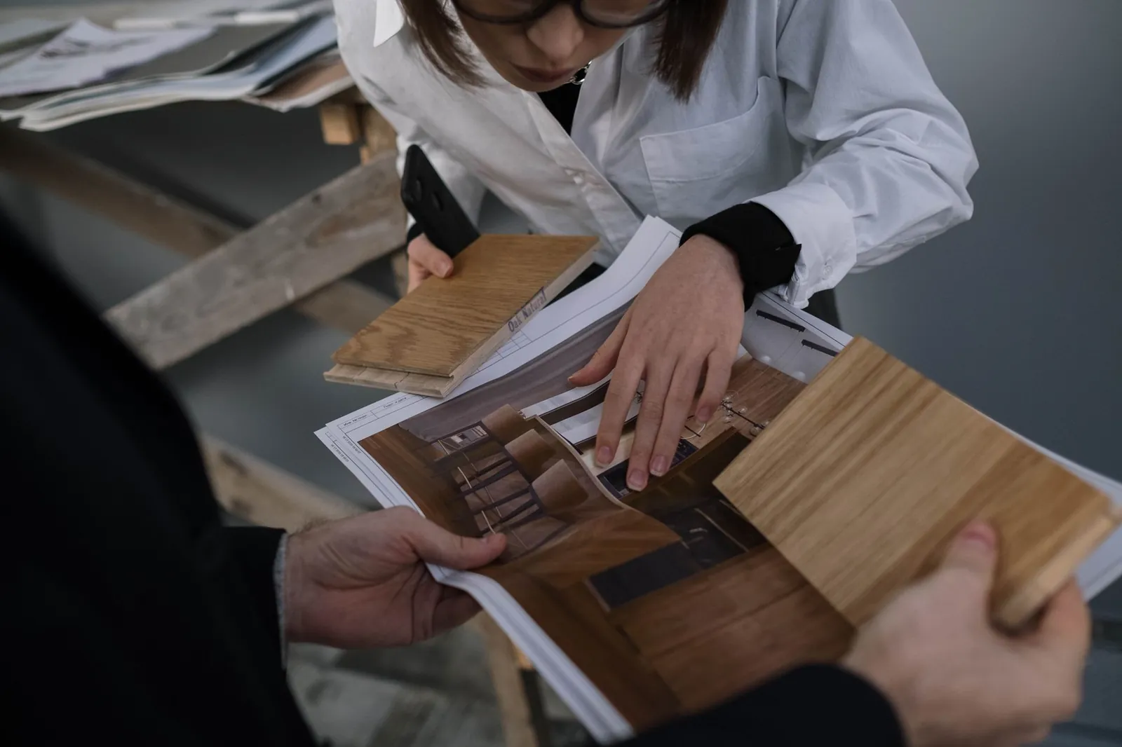 Two professionals collaborate on interior design by examining wood samples and design prints. Stock photo illustrating Rushil Decor's earning call story.