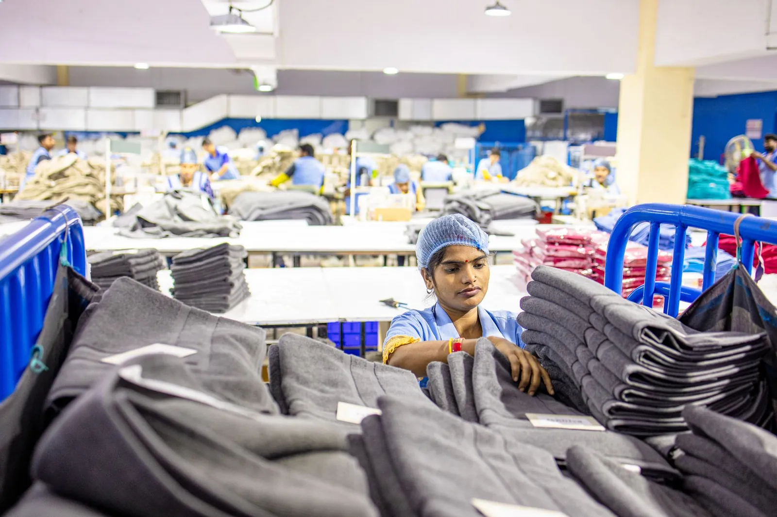 Textile worker sorting fabric piles in a busy South Asian apparel factory. Stock photo illustrating PDS's new order story.