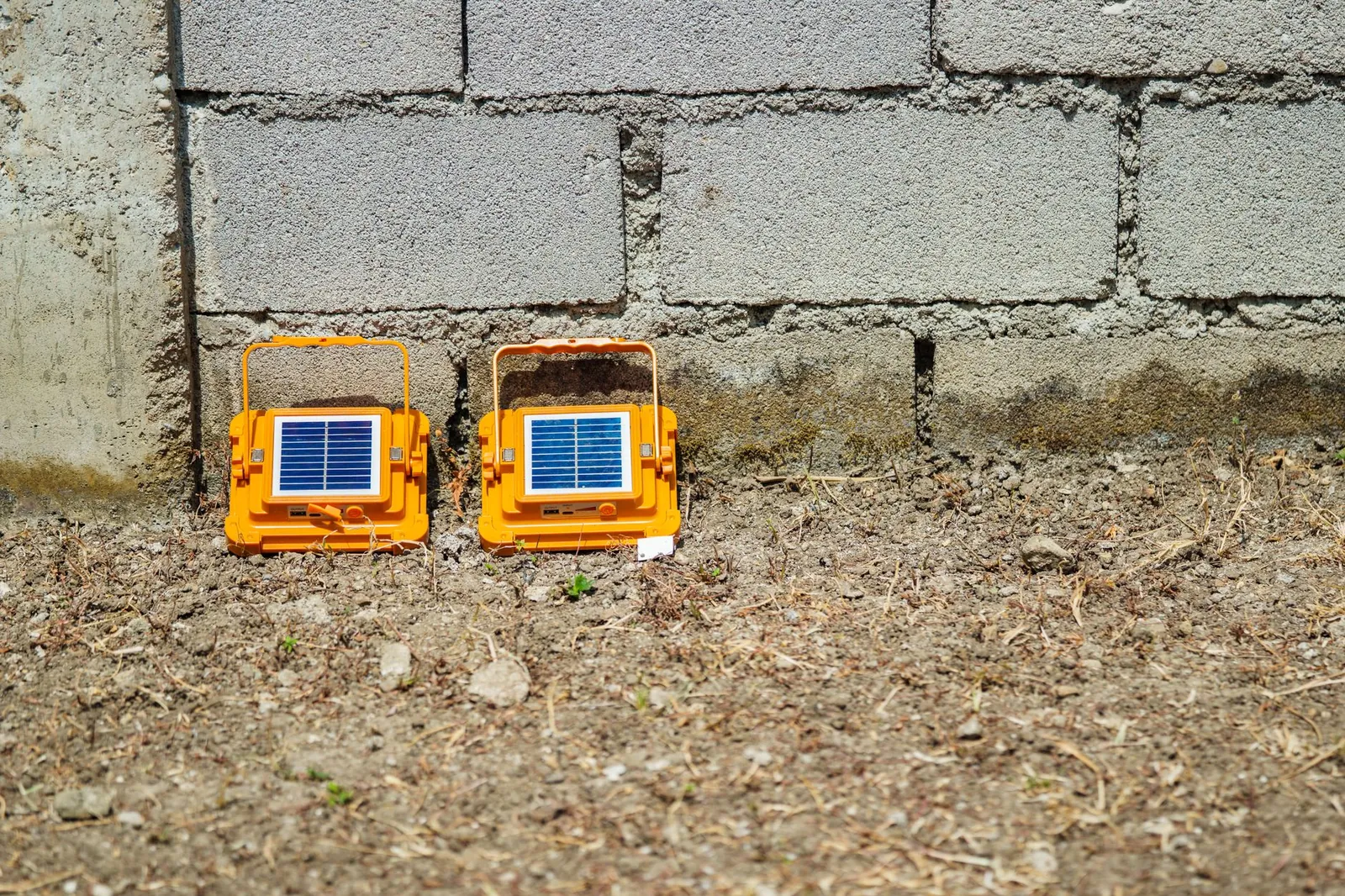 Bright orange portable solar lights sit against a concrete wall, capturing sunlight outdoors. Stock photo illustrating Solarworld Energy Solutions' earning call story.