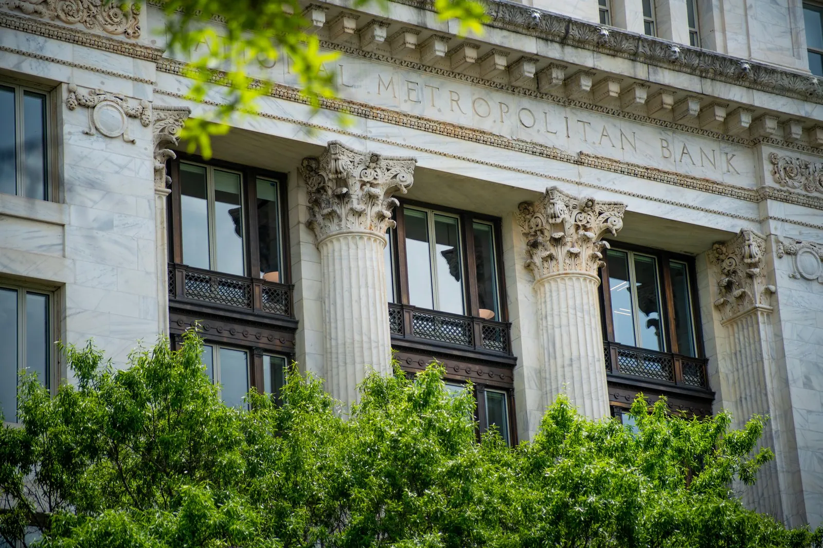 Close-up of the neoclassical columns and facade of Metropolitan Bank surrounded by greenery. Stock photo illustrating Canara Bank's fund raise story.