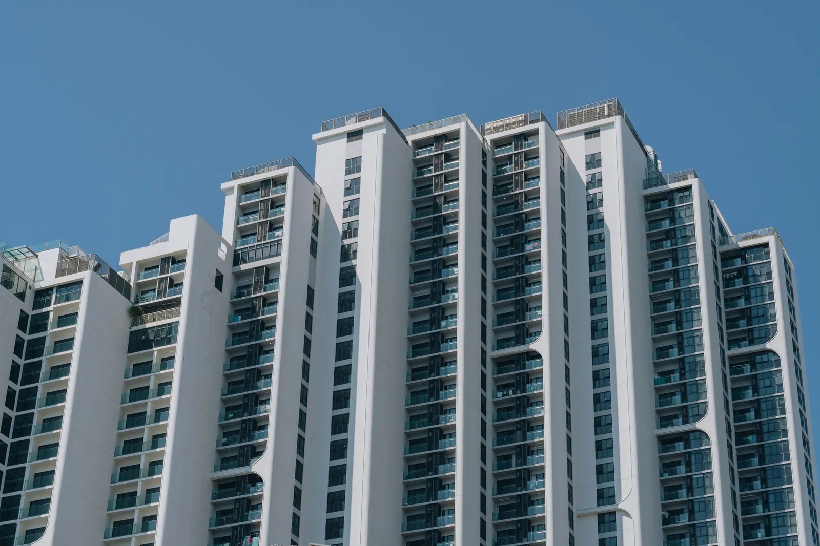 Contemporary high-rise apartment building with unique design and glass facades against a clear blue sky. Stock photo illustrating Max Estates' product launched story.
