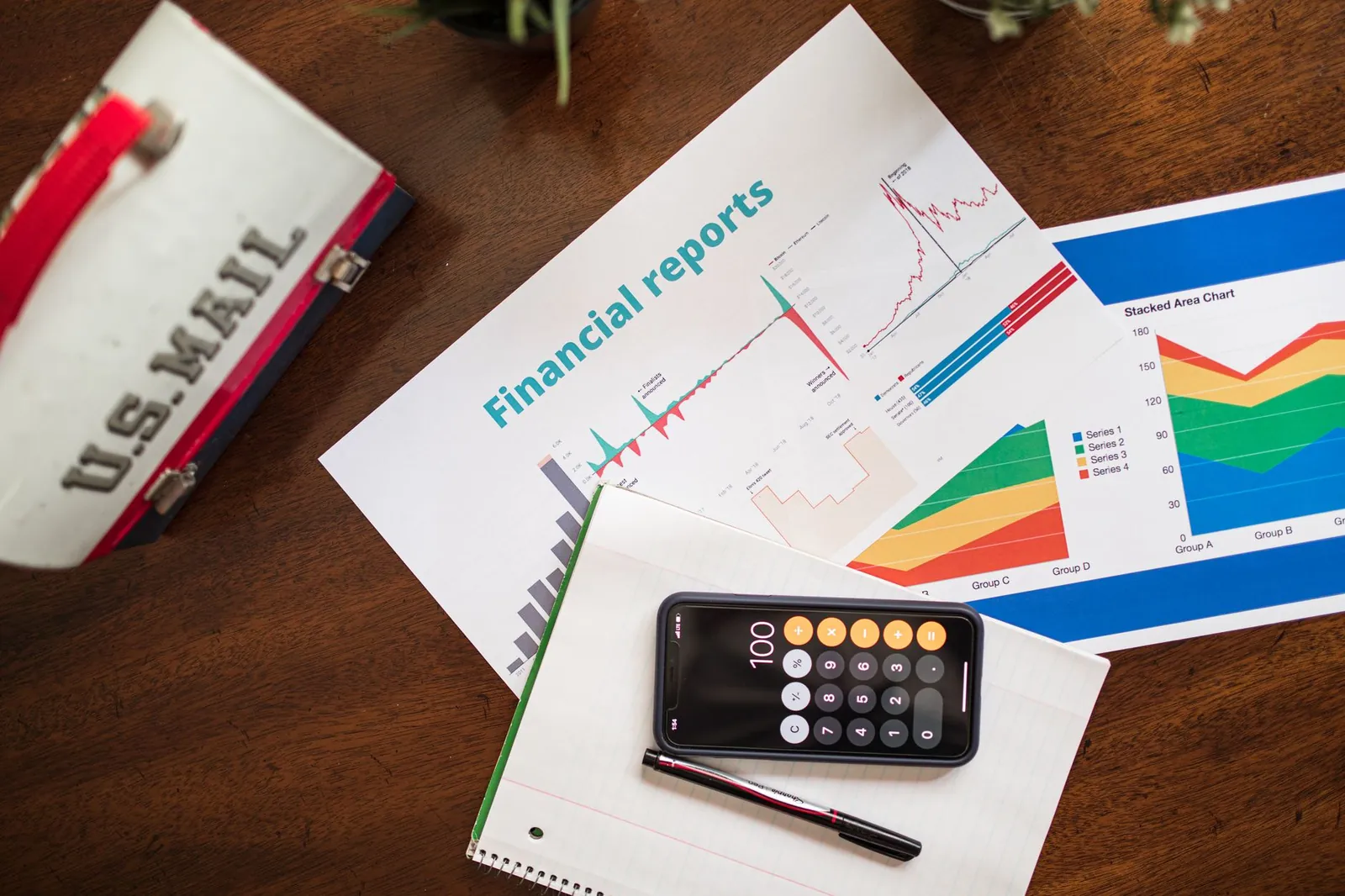 Overhead view of financial reports, charts, and a calculator on a desk. Stock photo for the ALFA News guide: Audited vs Unaudited Results: What Investors Should Know.