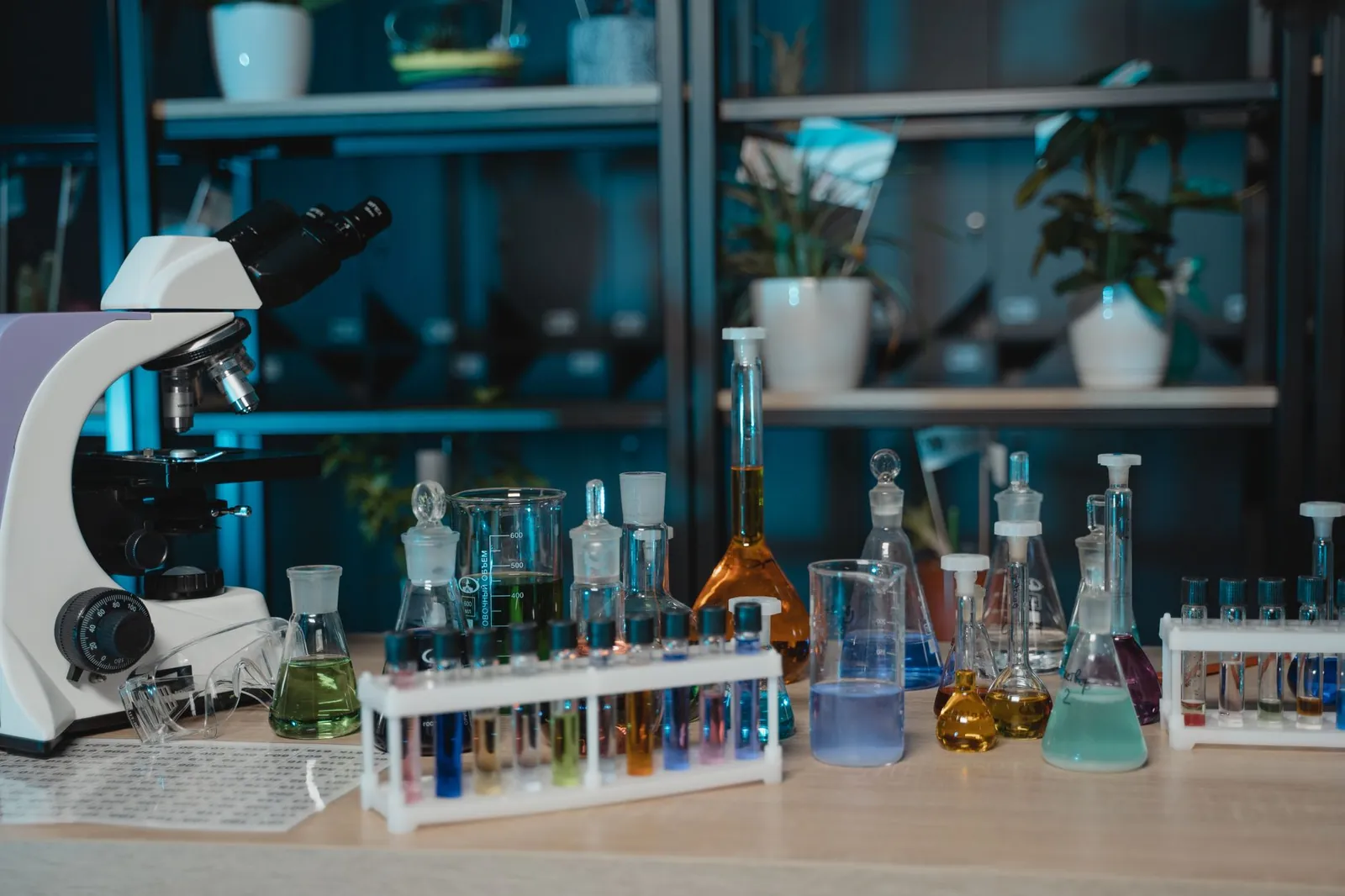 Vibrant laboratory setup with glassware, colored liquids, and a microscope for scientific research. Stock photo illustrating Sudarshan Pharma Industries' fund raise story.