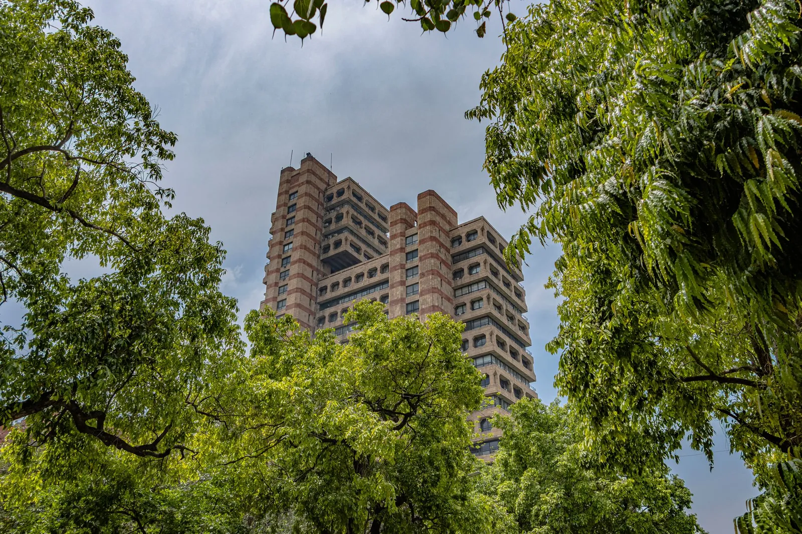A striking view of a brutalist architecture building surrounded by lush greenery in New Delhi. Stock photo illustrating Indiabulls' regulatory approval story.