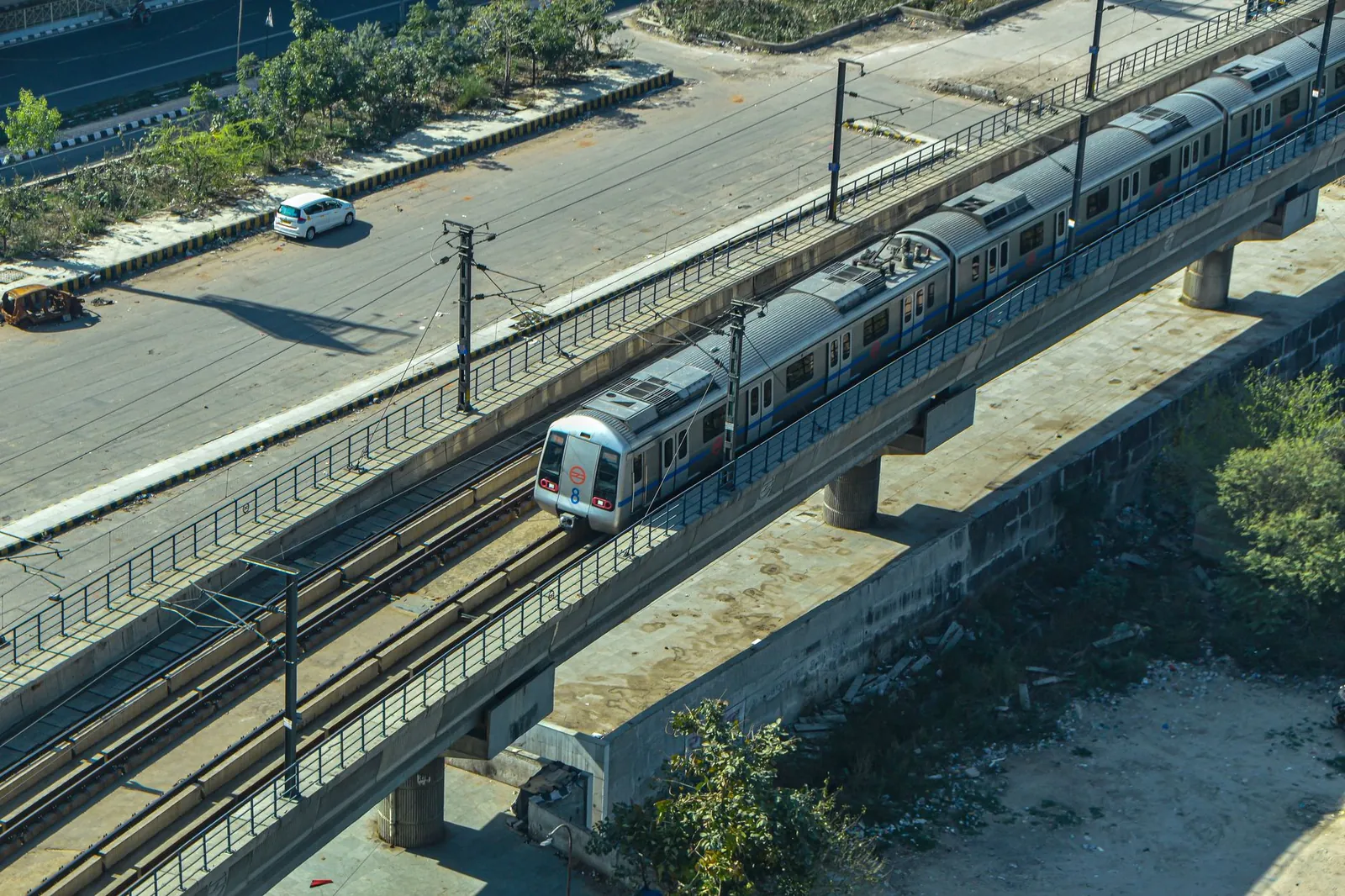 Aerial shot of a metro train crossing a concrete bridge in a city landscape. Stock photo illustrating C.E. Info Systems' partnership story.