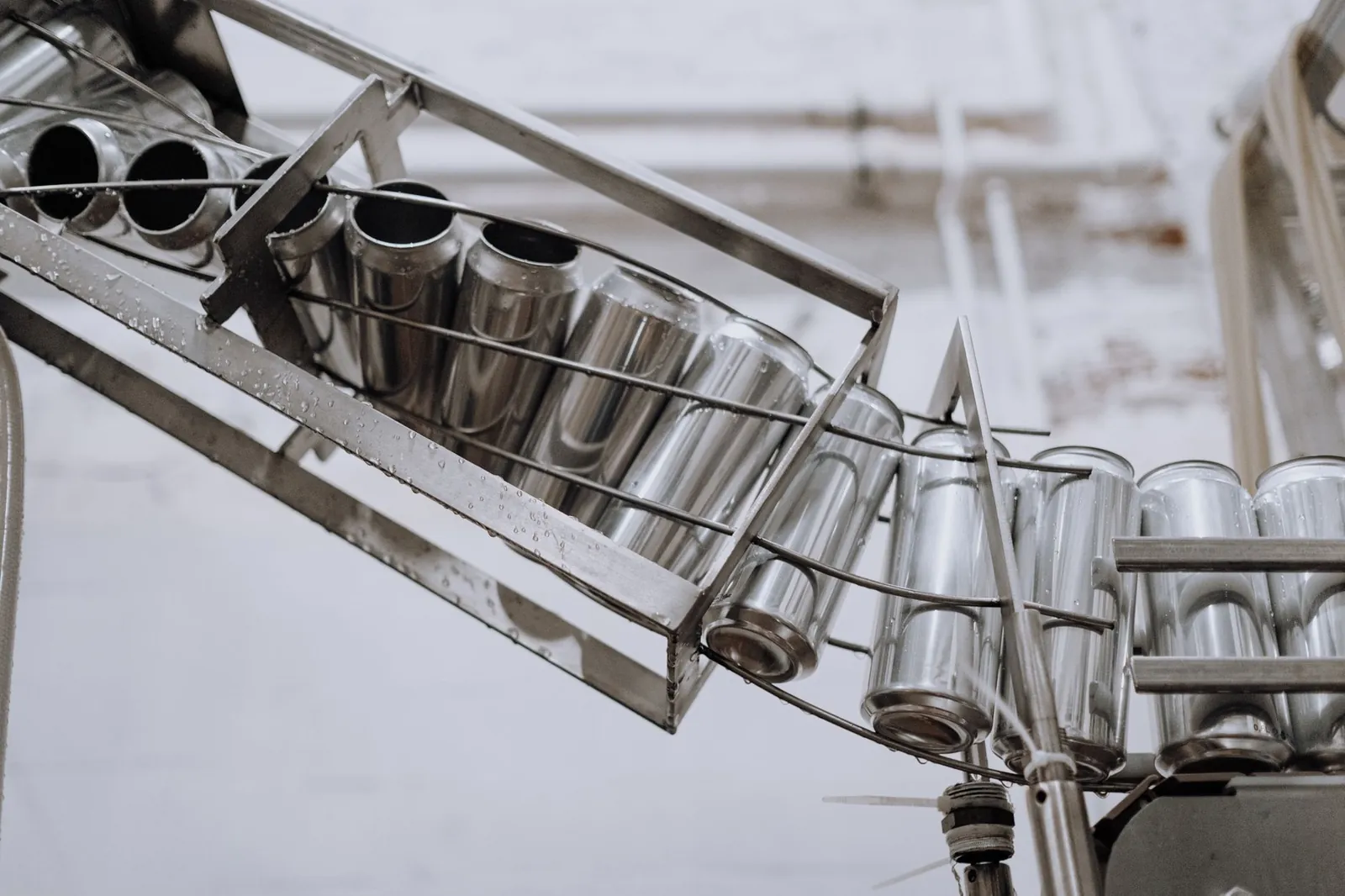 Conveyor belt with empty aluminum cans in a factory setting, showcasing production equipment. Stock photo illustrating Sambhv Steel Tubes' fund raise story.