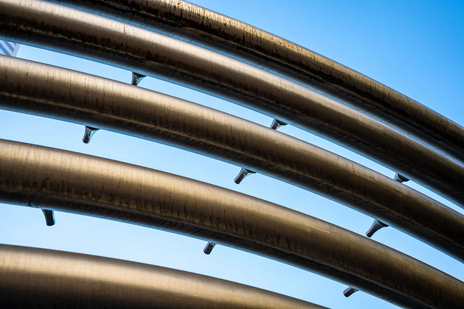 Close-up of metallic pipes with a modern, futuristic look against a clear blue sky. Stock photo illustrating Welspun Corp's earning call story.