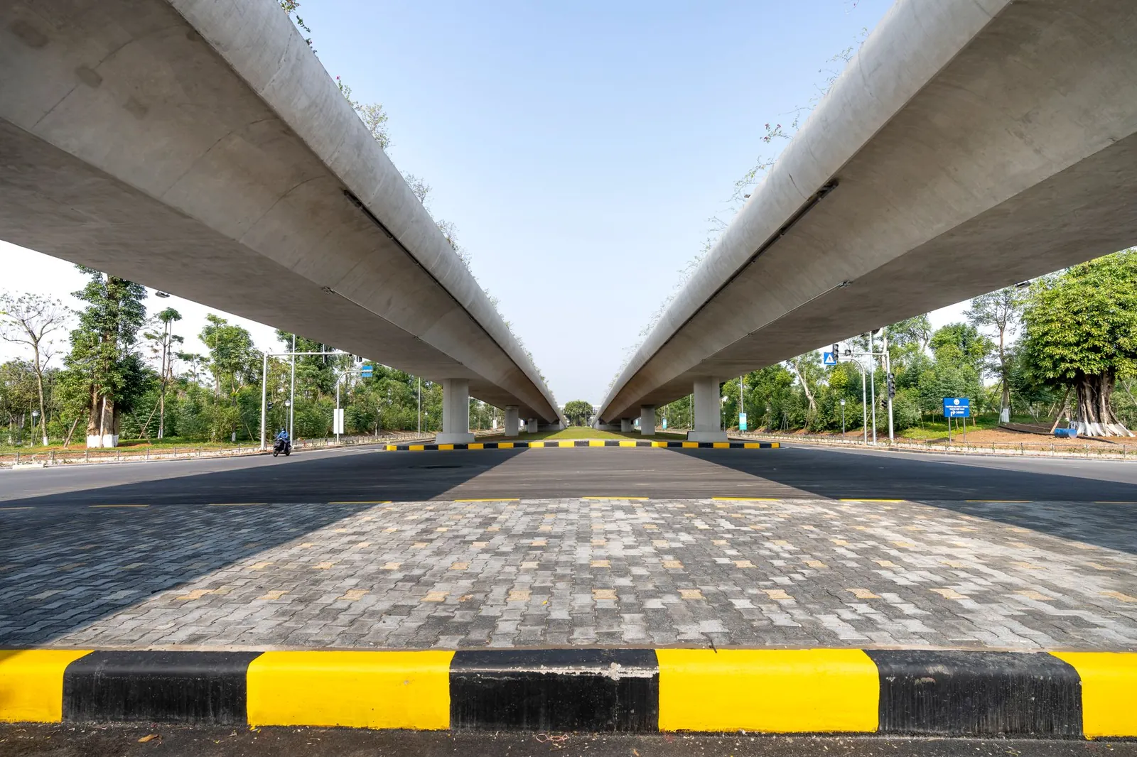 Concrete elevated highways over asphalt road between lush greenery in suburb under blue sky. Stock photo illustrating RITES's partnership story.