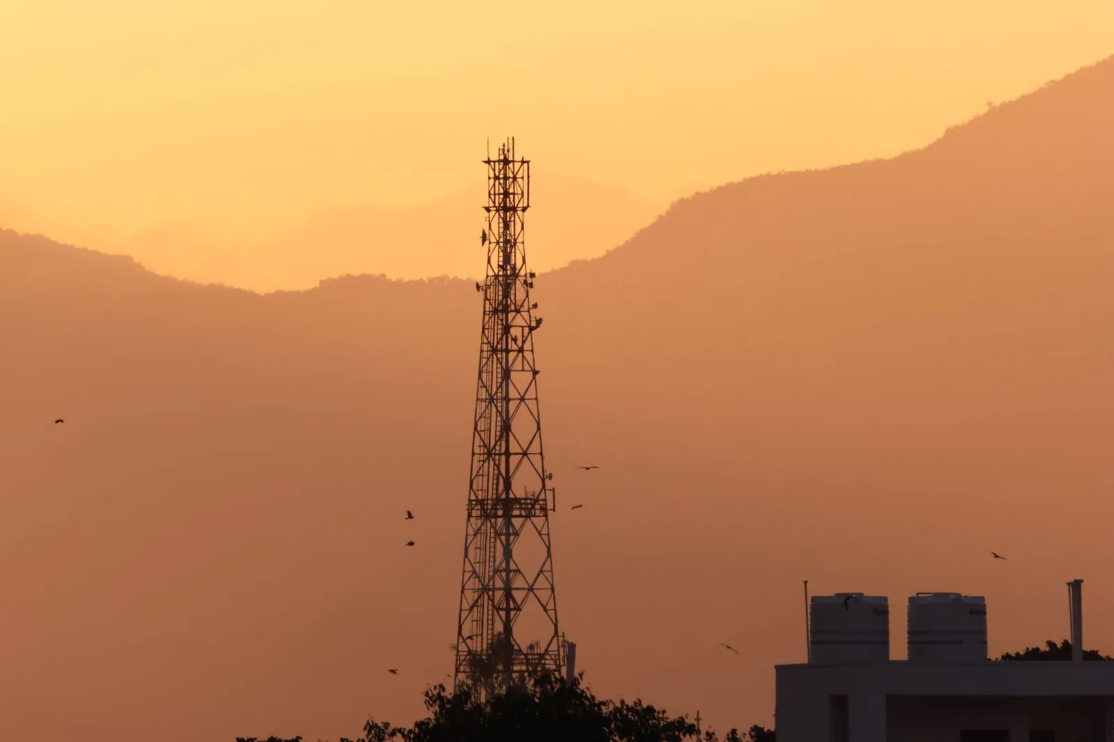 Silhouette of a communication tower against a vibrant sunset in Tamil Nadu, India. Stock photo illustrating Vodafone Idea's earning call story.