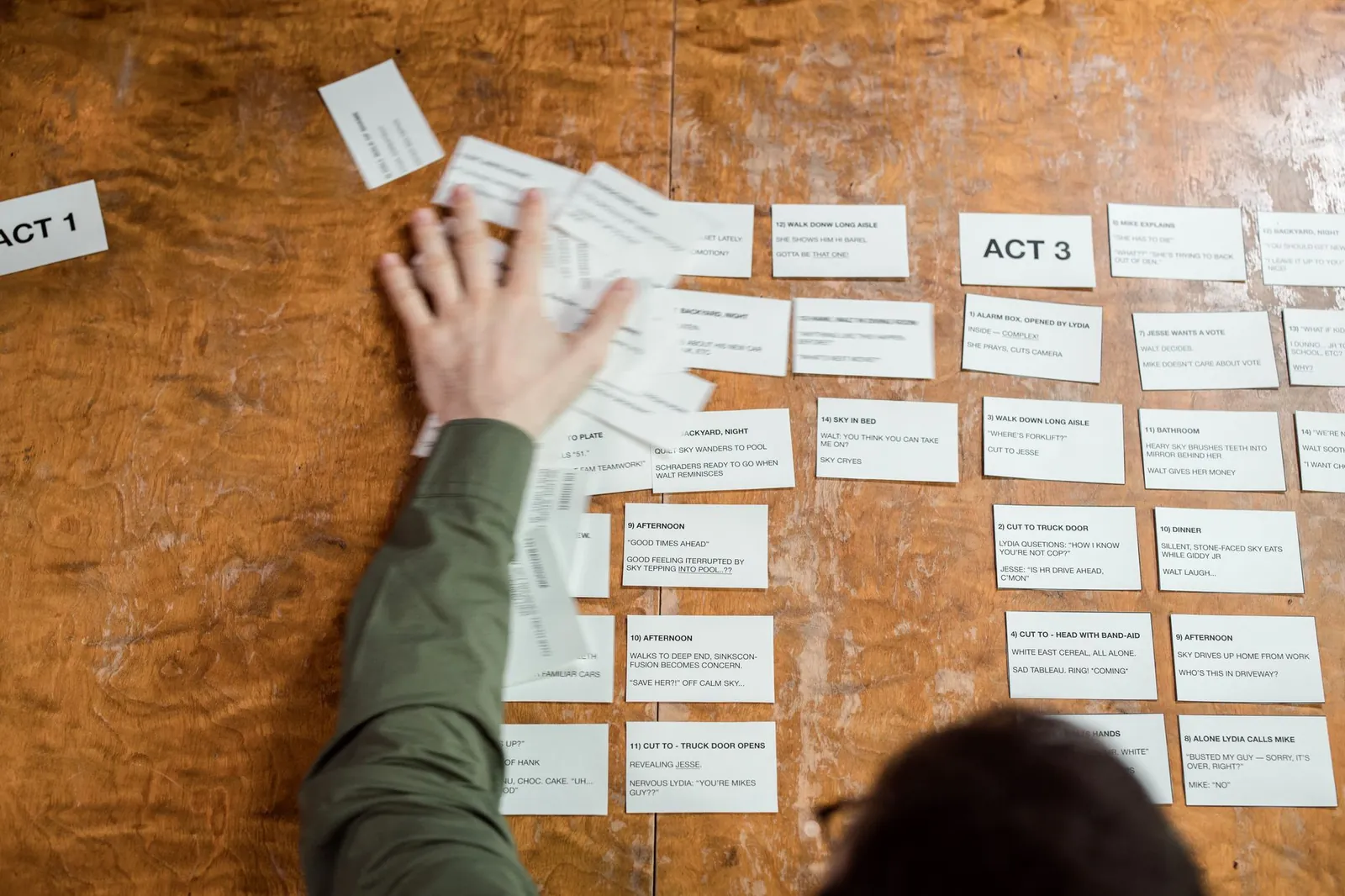 A person arranging storyboard cards on a wooden table for a film script planning session. Stock photo illustrating Panorama Studios International's partnership story.