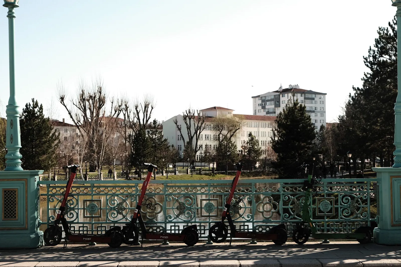 Ornate railing with scooters in a park setting, urban area, bright day. Stock photo illustrating Ather Energy's fund raise story.