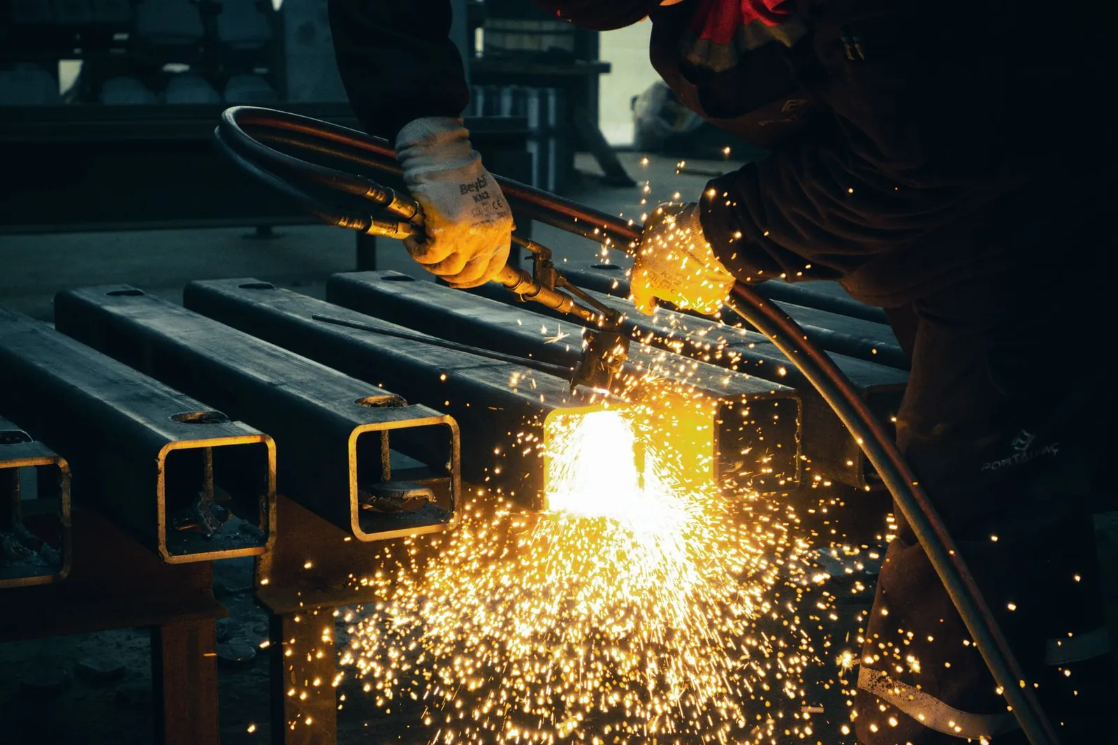 A welder sparks metal beams indoors in an industrial factory setting. Stock photo illustrating Magnus Steel and Infra's new order story.