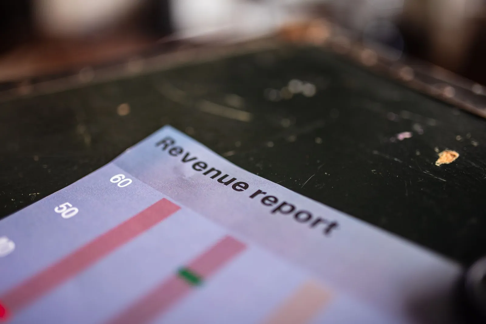 Detailed view of a revenue report featuring a bar chart in an office setting. Stock photo for the ALFA News guide: Order Book vs Revenue: A Guide to Stock Market Execution Risk.