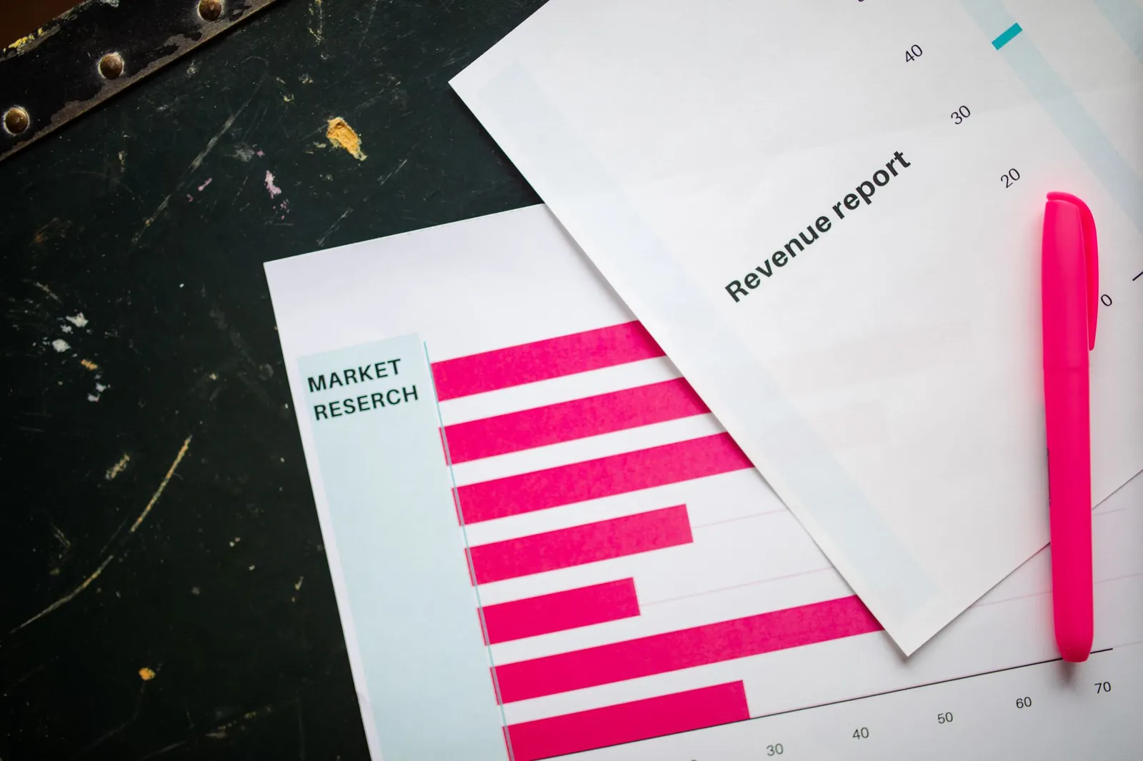 Close-up of market research charts and a revenue report with a pink pen on a desk. Stock photo illustrating Virtual Galaxy Infotech's earning call story.
