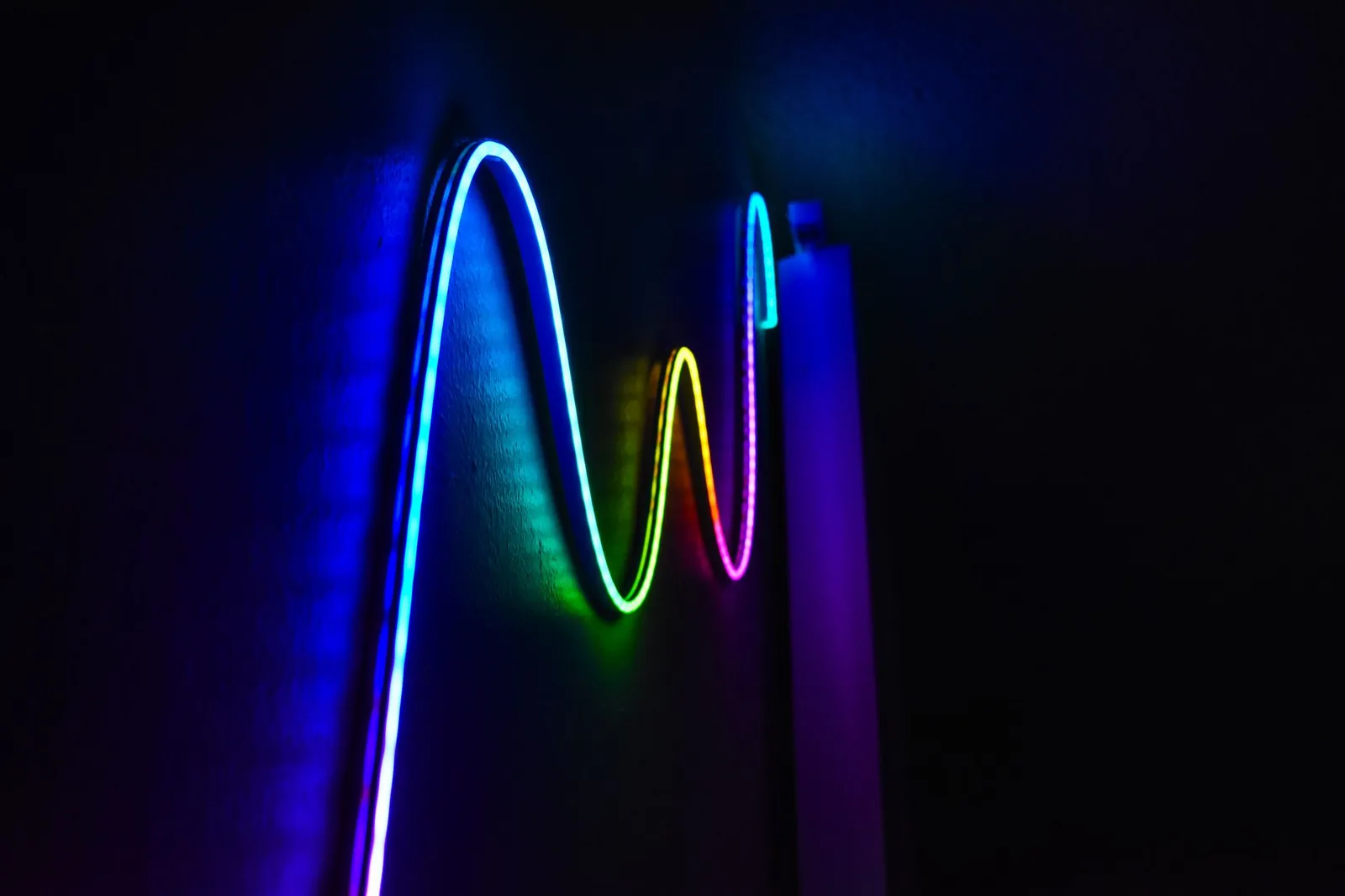 Colorful neon wave pattern LED lights illuminating a dark room for a modern home decor aesthetic. Stock photo illustrating Kundan Edifice's product launched story.