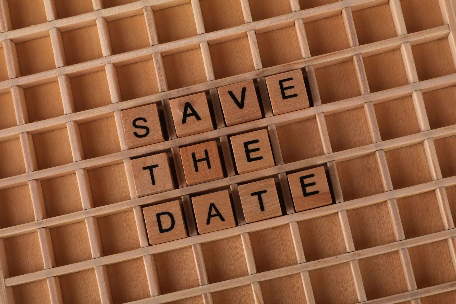 Top view of 'Save the Date' message using wooden letter blocks on a grid pattern background. Stock photo for the ALFA News guide: Record Date vs Ex-Date in Indian Stock Markets.