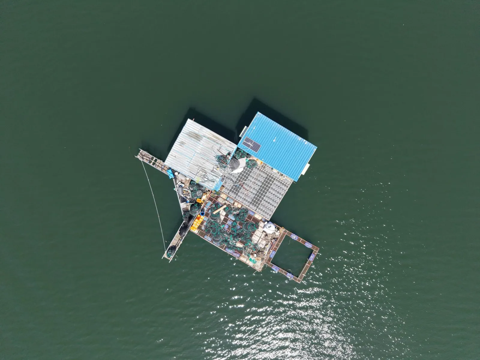 Aerial shot of a floating fishing platform with equipment in calm waters, ideal for marine concepts. Stock photo illustrating Tata Power Company's partnership story.