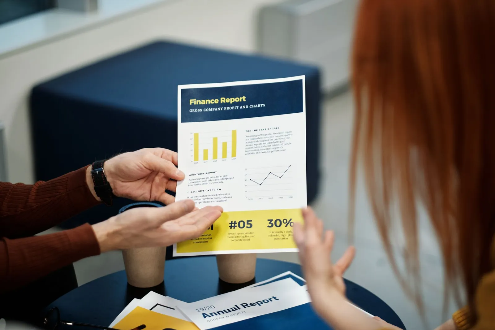 Two individuals analyzing a finance report chart at a business meeting in an office setting. Stock photo for the ALFA News guide: Annual Report Filing in India: What Investors Should Check.