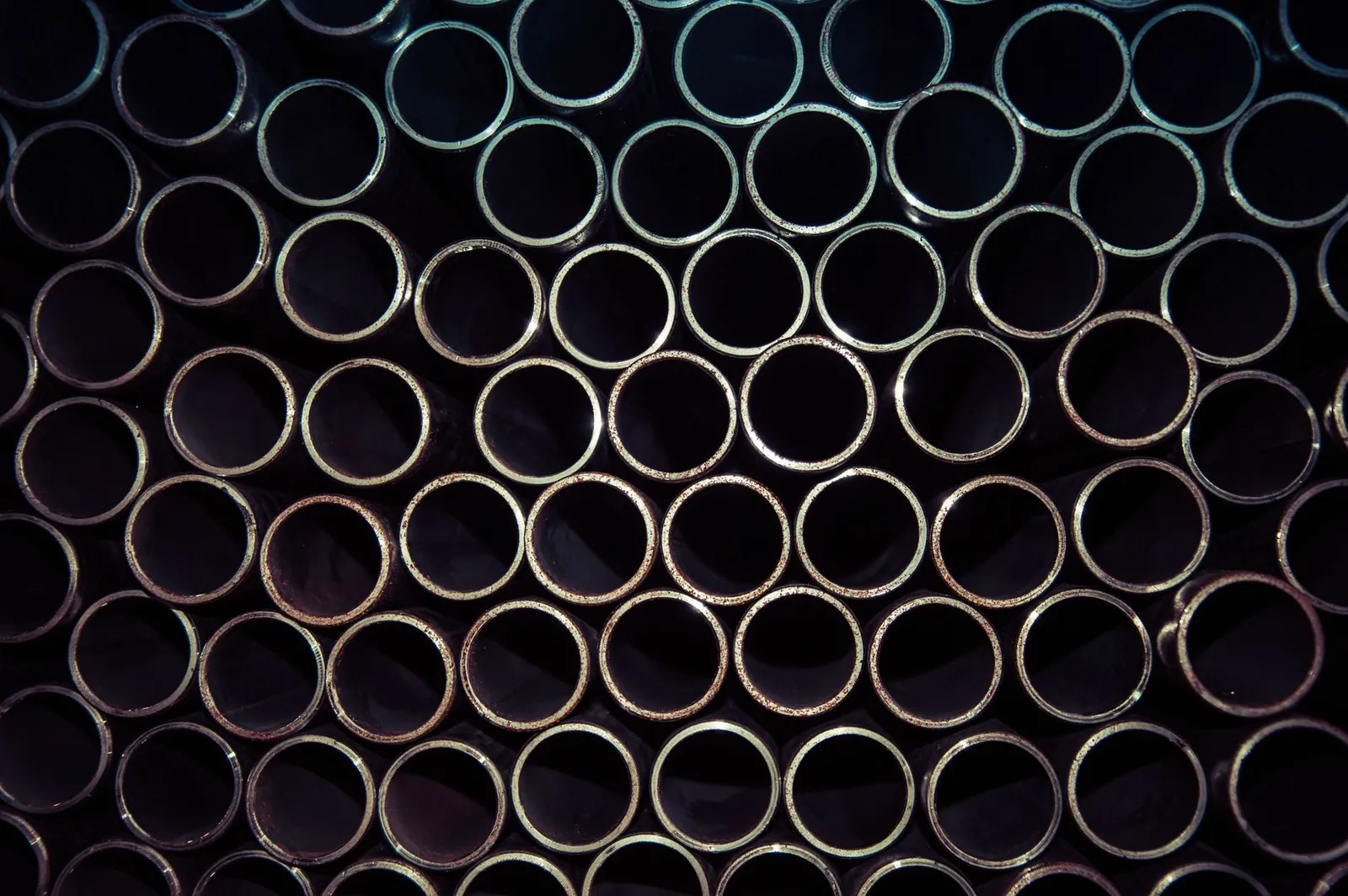 A detailed macro shot of stacked metal tubes forming a circular pattern, highlighting industrial design. Stock photo illustrating Surani Steel Tubes' fund raise story.