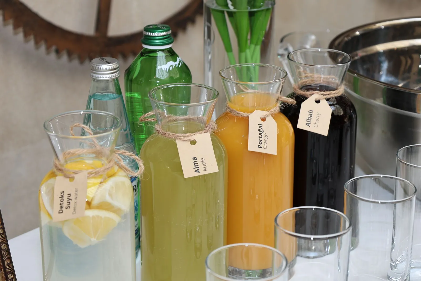 Vibrant assortment of fresh juices in labeled glass bottles with water bottles and glasses arranged outside on a table. Stock photo illustrating NHC Foods' expansion story.