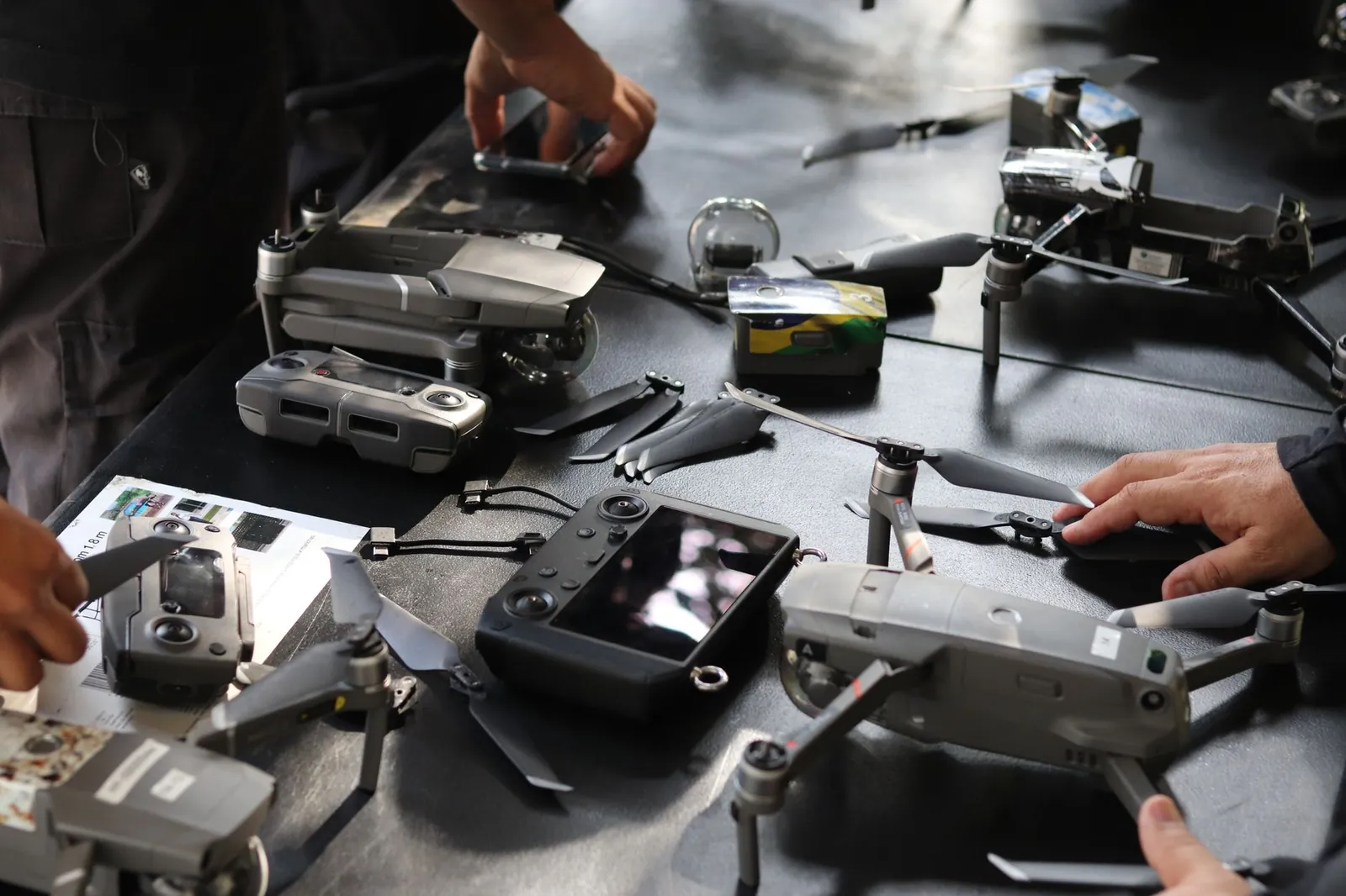 Close-up of hands setting up drones and equipment indoors, showcasing technology and teamwork. Stock photo illustrating Optivalue Tek Consulting's new order story.