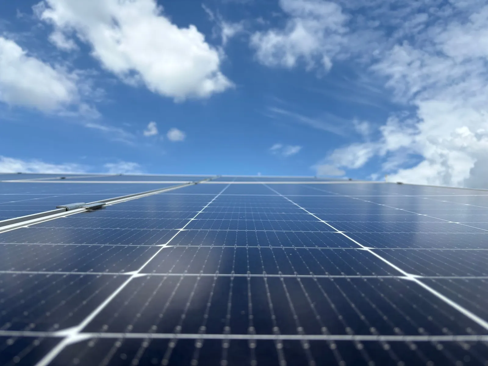 Close-up of solar panels with a clear blue sky and fluffy clouds in Dehradun, India. Stock photo illustrating Insolation Energy's earning call story.