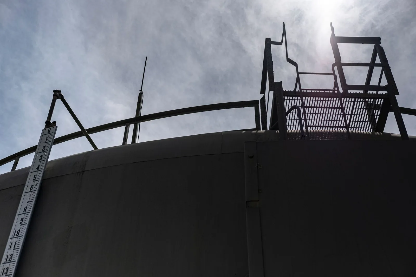 Dramatic low angle shot of a storage tank and metal ladder against a bright sky. Stock photo illustrating Axis Solutions' product launched story.