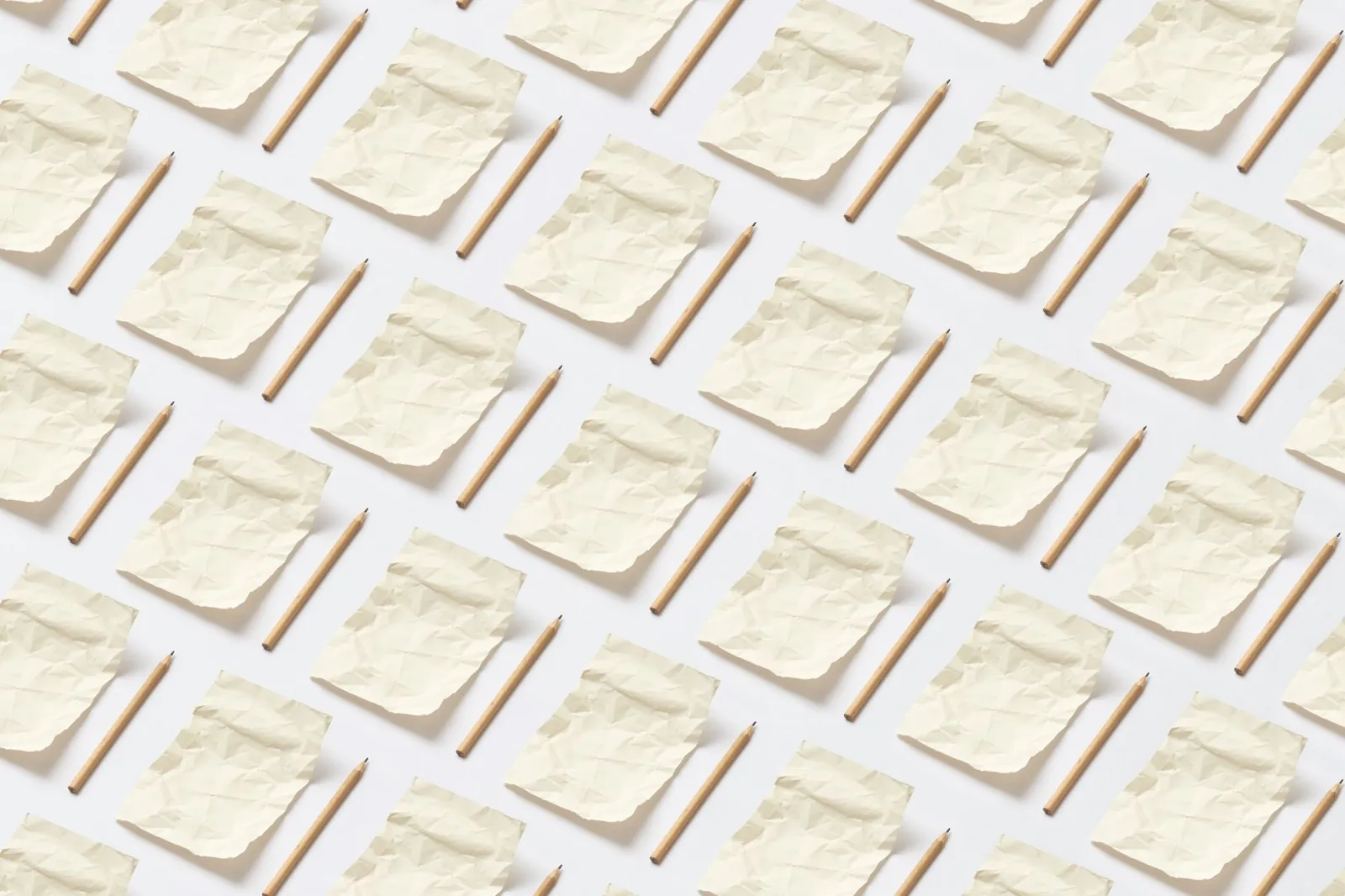 A minimalist pattern featuring crumpled papers and pencils on a white surface. Stock photo illustrating Vilas Transcore's product launched story.