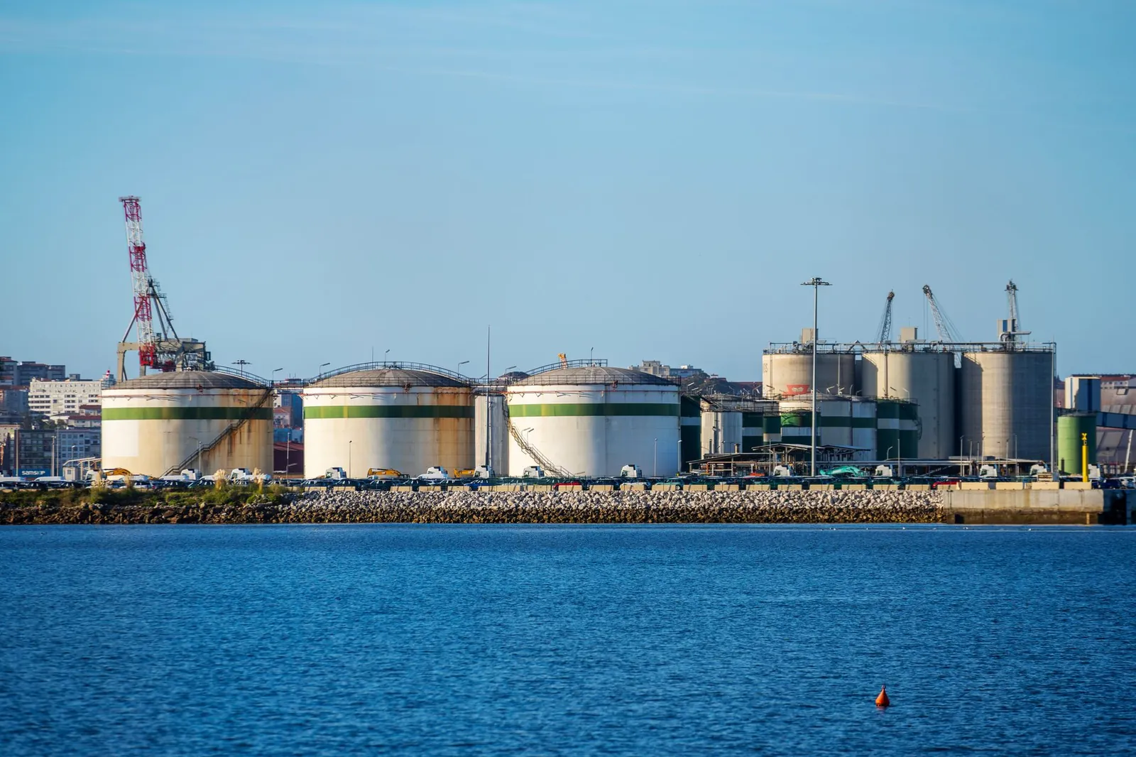 Large storage tanks at an industrial port facility by the water under clear blue skies. Stock photo illustrating Pace Digitek's expansion story.